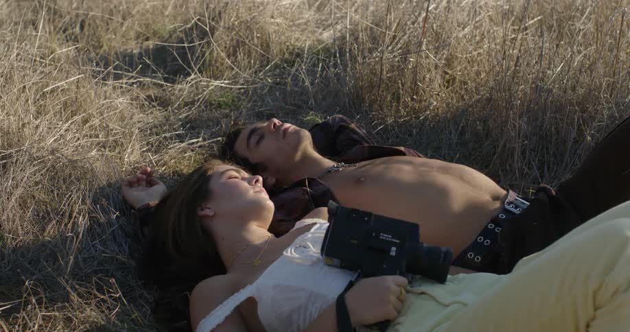A man and woman lay in the grass together