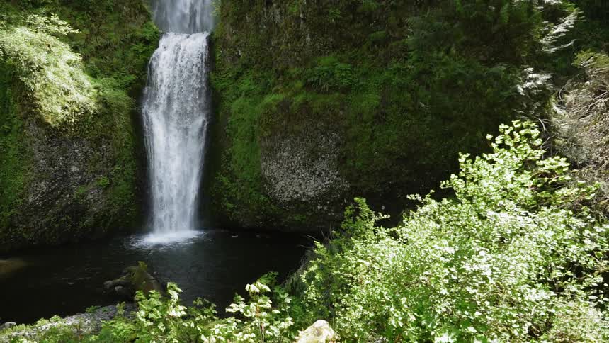 Water falls from the cliff down into the ravine
