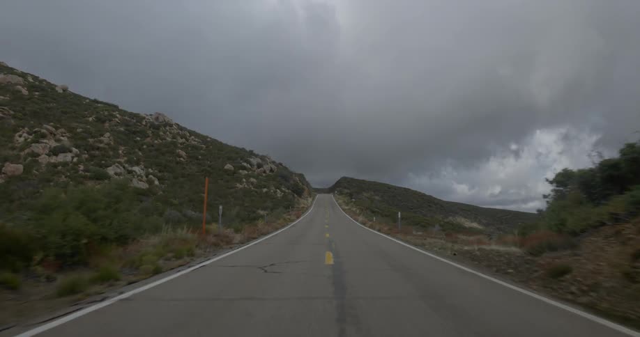Traveling down a paved remote road towards a cloudy sky