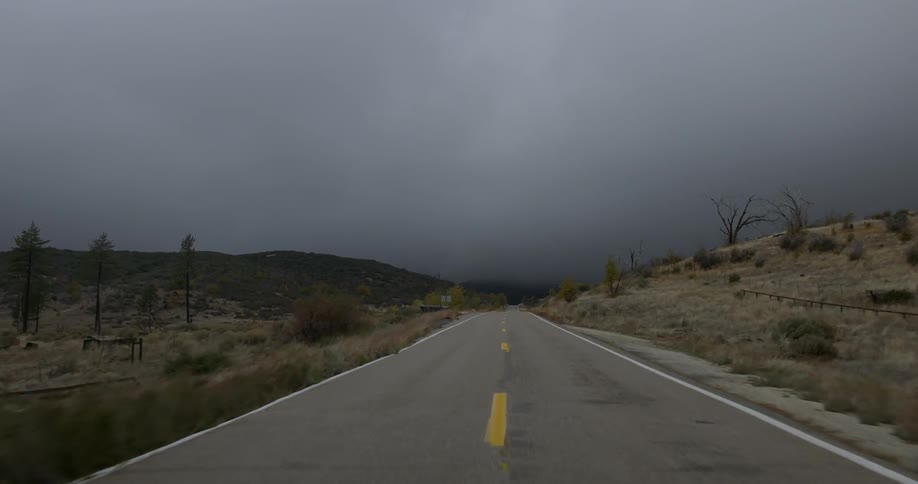 A vehicle drives down a desert road