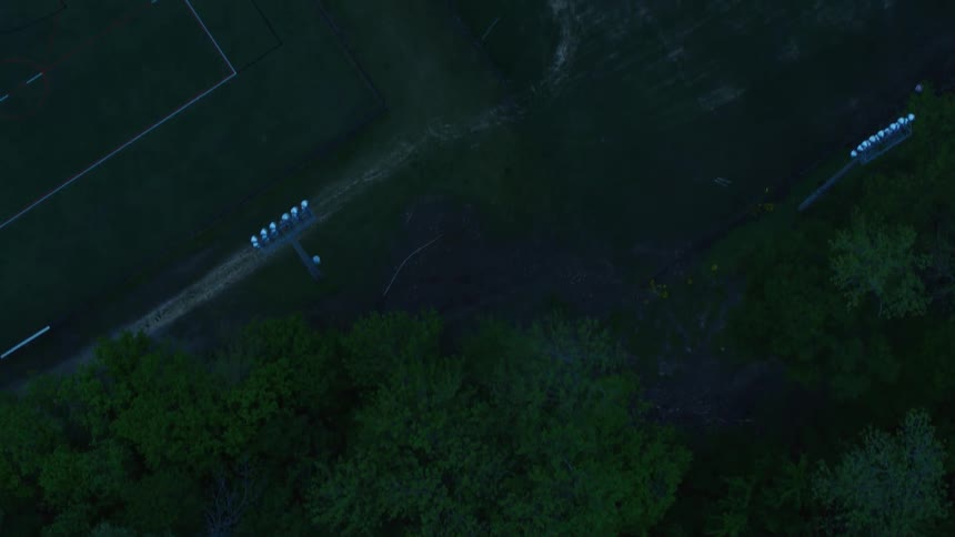An athletic field sits next to a grove of trees