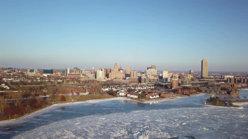 Ice is covering a waterway near a city on a sunny day