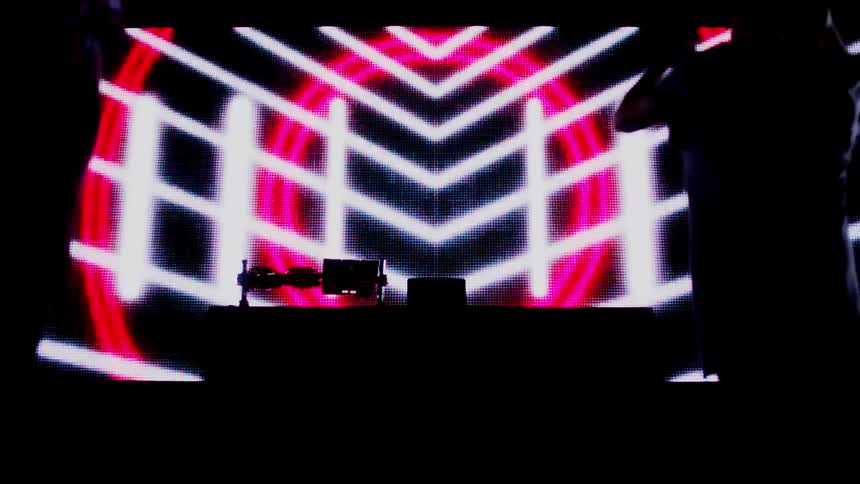 Two djs perform in front of a projection screen