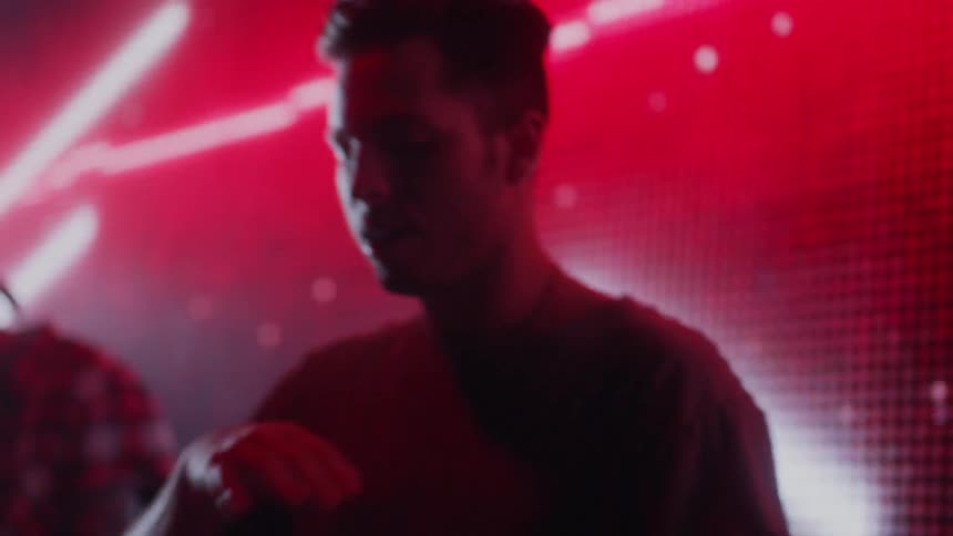 A dj dances in front of a screen of lights