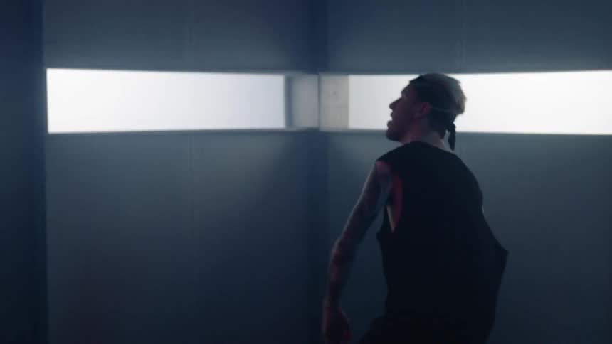 A man is dancing and thrashing about in a room with windows