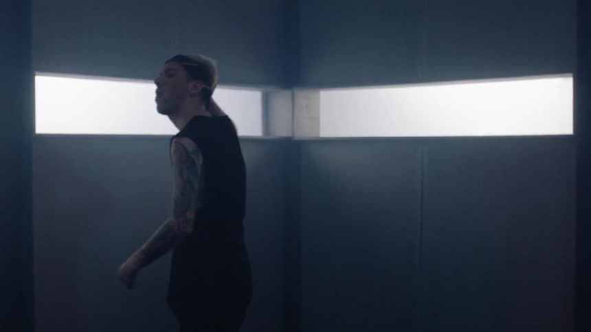 A man dances inside a room with narrow windows