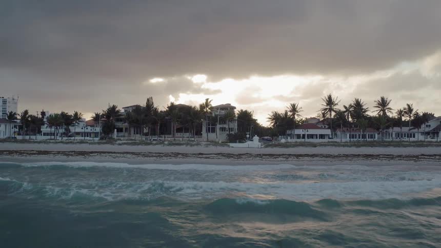 Ocean waves flow towards a shoreline at sunset