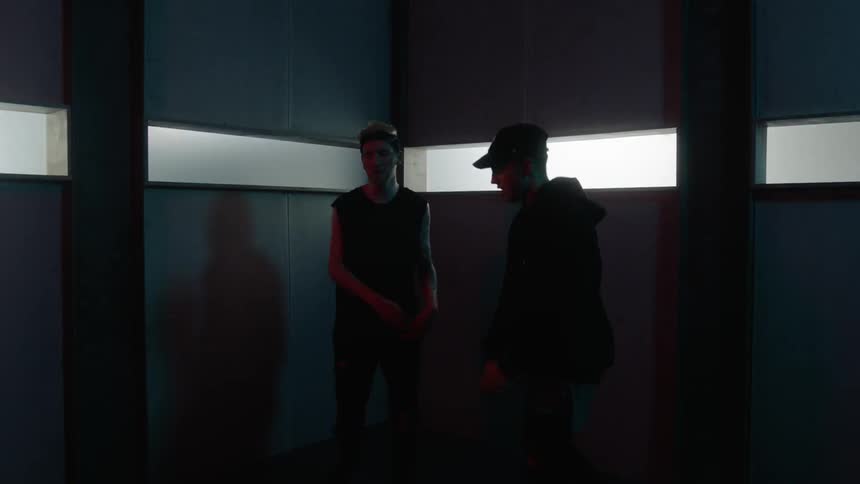 Two boys are dancing inside a room with lights flashing through windows