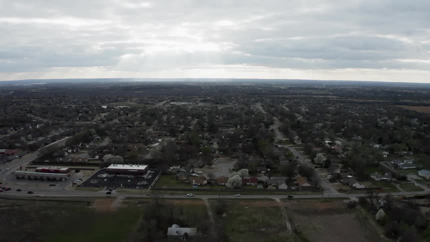 Cars travel on roads past buildings on a cloudy day