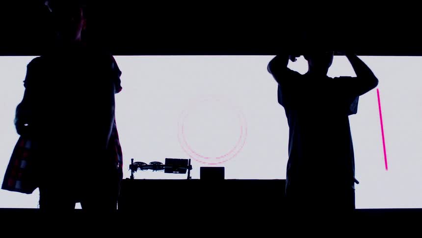 Two djs walk behind the turntable