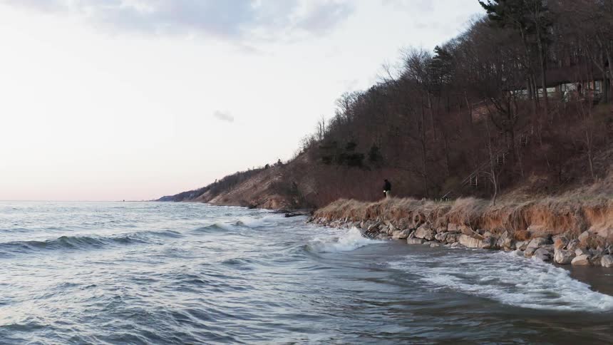 Person watching ocean waves roll in on cloudy day