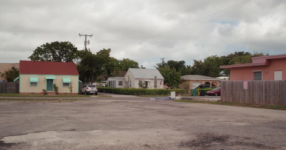 Gray clouds are hanging over a neighborhood and vacant lot in daytime