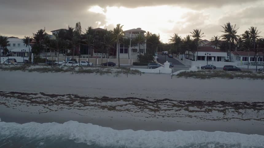 Cars travel on a road by the beach where ocean waves come to shore
