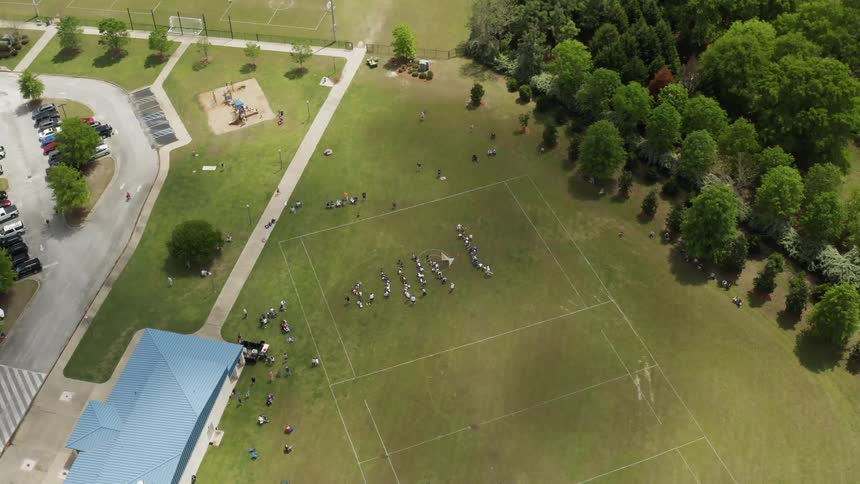 Spectators and players are gathered on a soccer field during the day