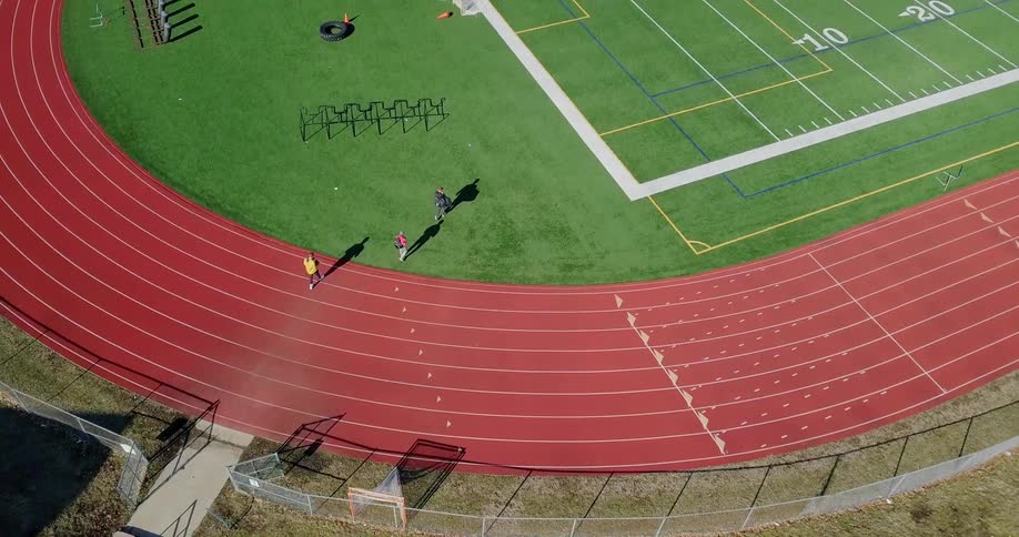 Three people walk over the tracks onto the field