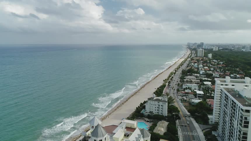 The waves crash against the sand of the coastal town
