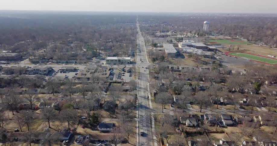 Cars travel on roads through a neighborhood