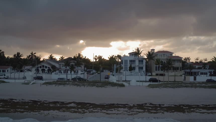 The sun is setting on a stormy sky by the shore