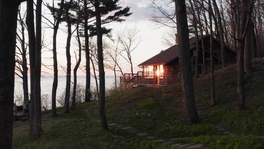 The house is right on the hill by the trees