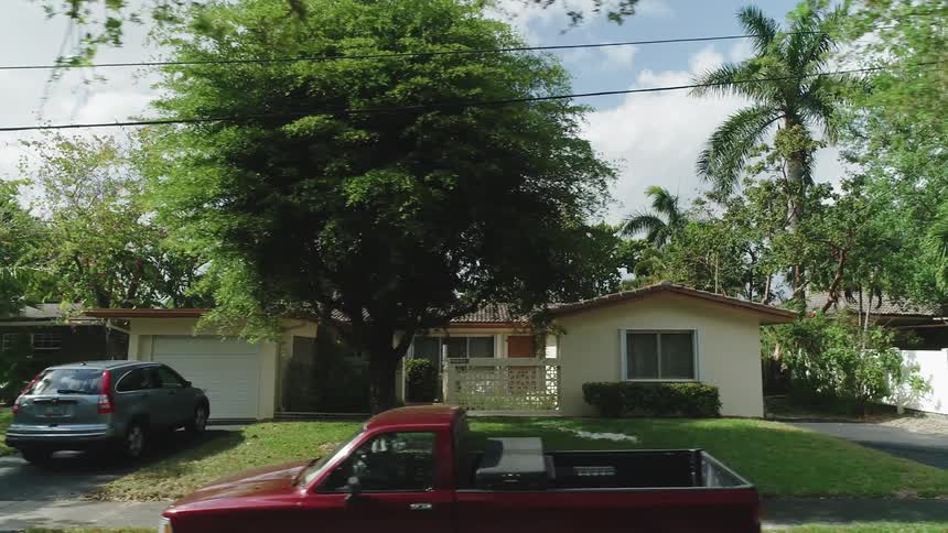 Passing houses and cars in neighborhood on sunny day