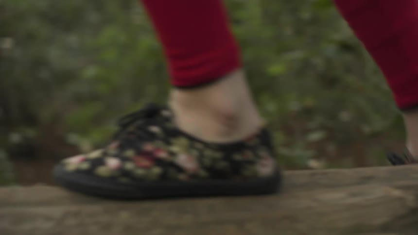 Close up of feet climbing up onto a fallen tree