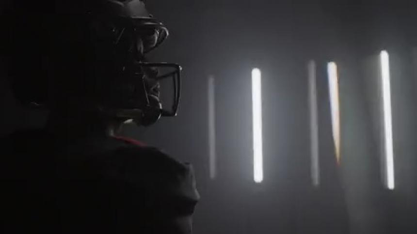 A football player stands in a room with flashing lights