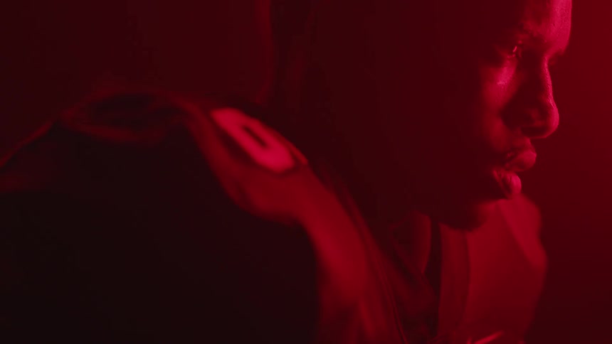 A football is breathing heavy and concentrating as he stands in a room bathed in red light