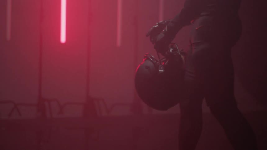 A football player walks through a room with glowing red lights