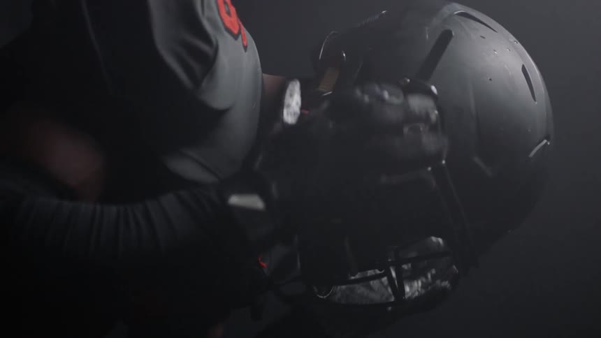 A football player puts on his helmet
