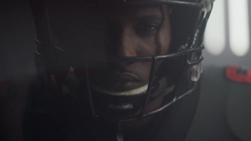 A football player stands in a room with flashing lights