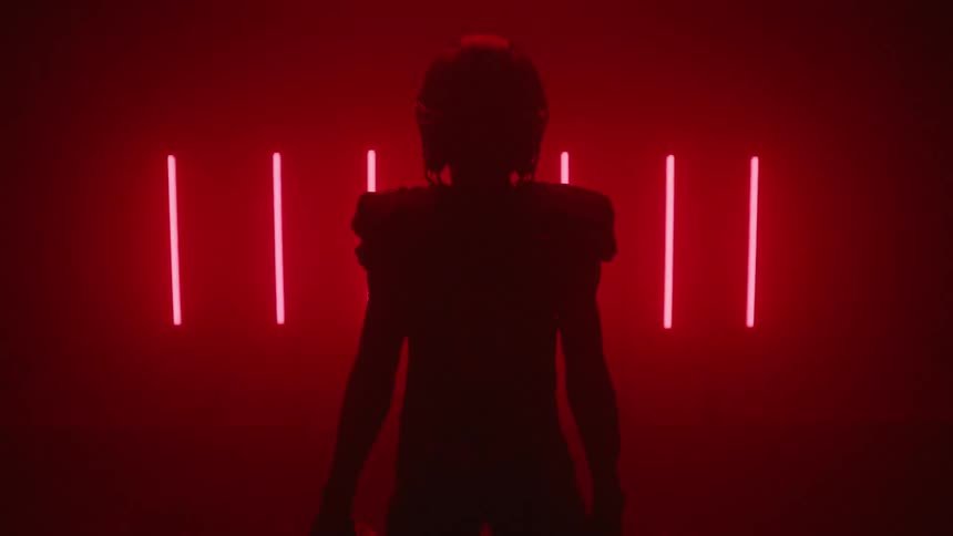 The football player stands in the dark by red lights