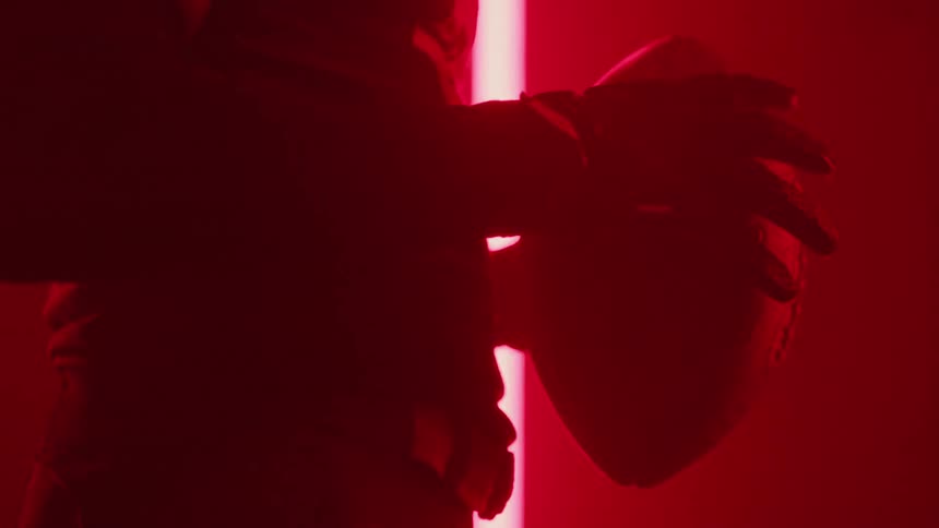 Flashing lights surround a football player in a room while he holds a football