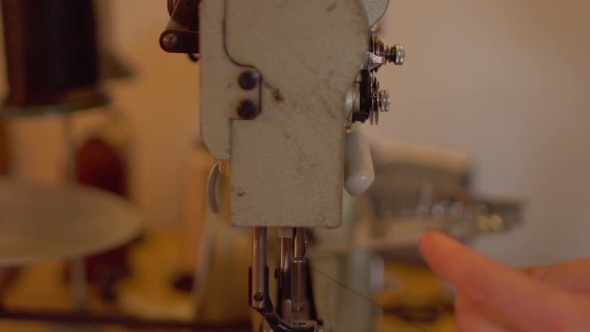 A man threads a sewing machine