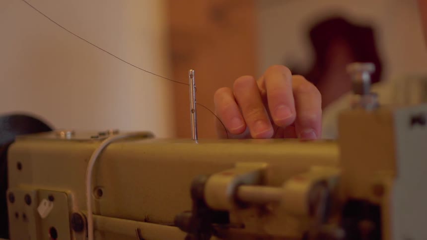 A man threads a sewing machine