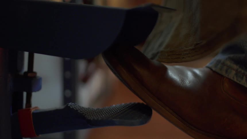 A foot pushes down on a metal pedal