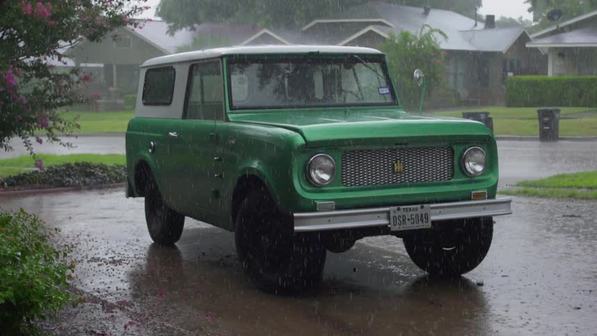Green and white vehicle sits in the rain