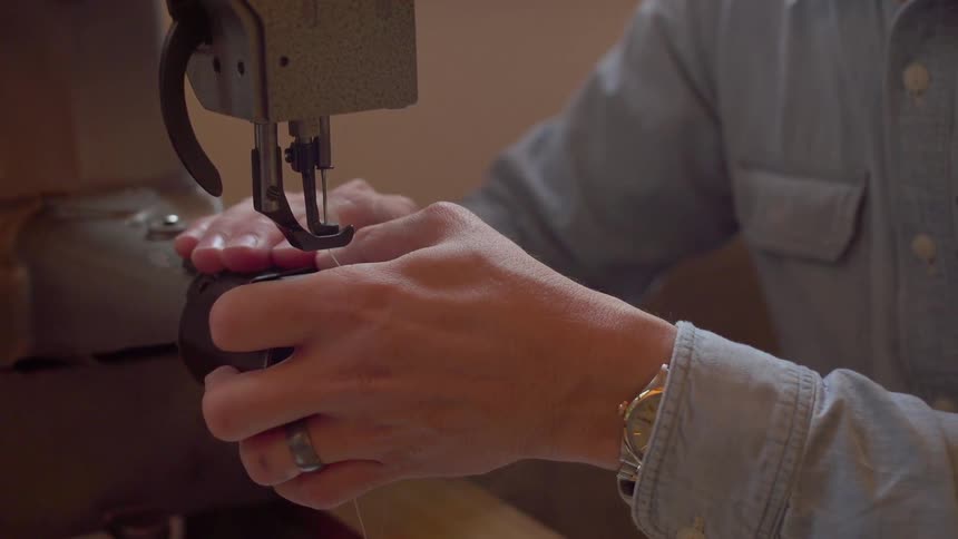 Man slides the base of a sewing machine with his hands