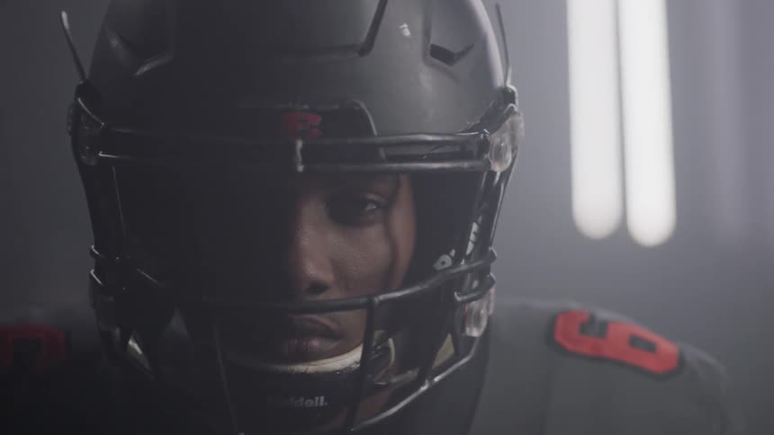 A football player stands in a room with flashing lights