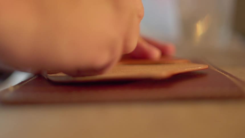 A person uses a hand tool to work on leather