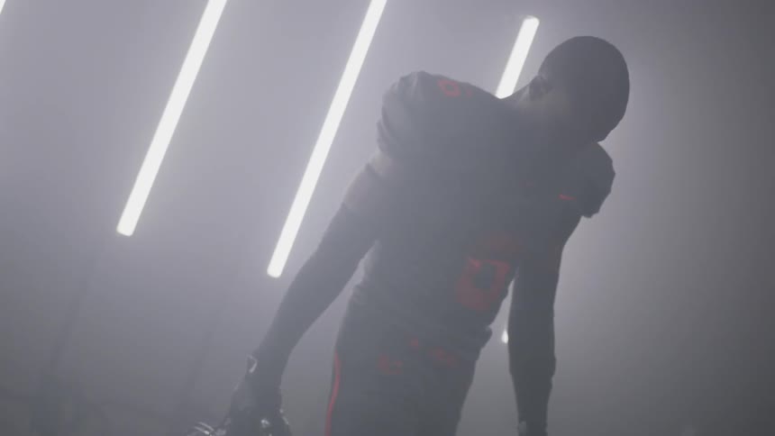 Man wearing football gear walks near the bright lights
