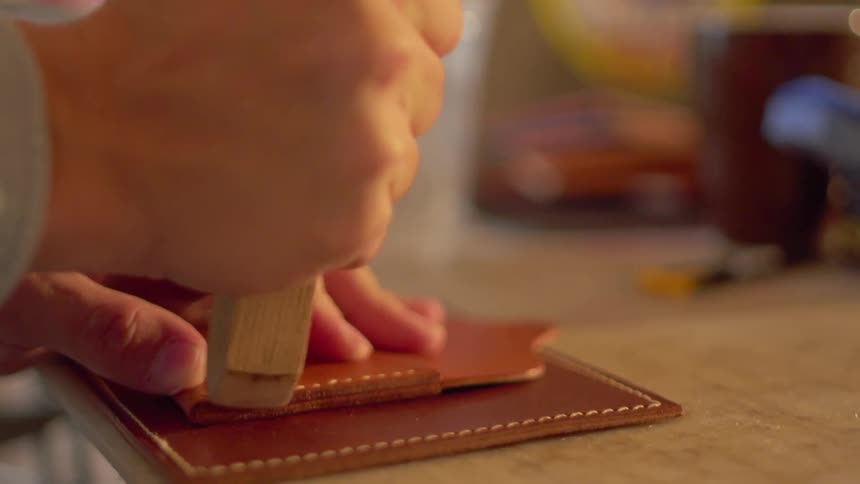 A man makes leather wallets in a workshop