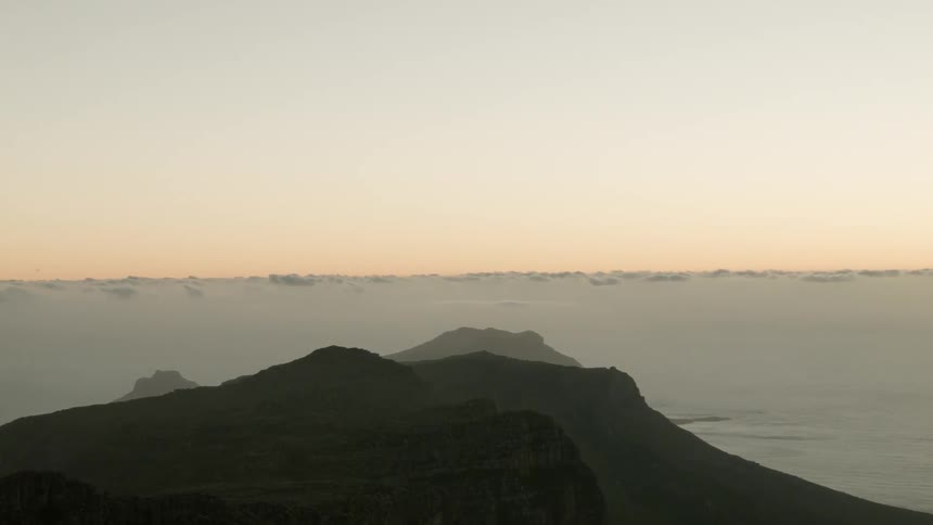 The sun sets on the water near mountains