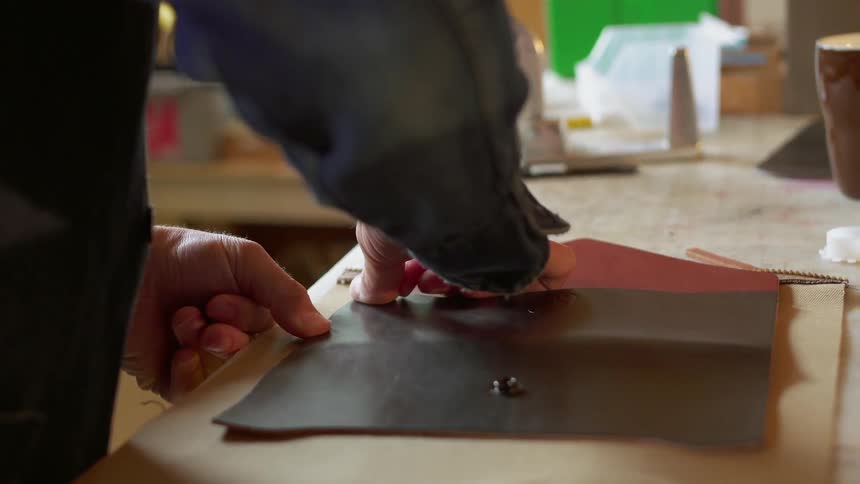 A man works with leather on a desktop