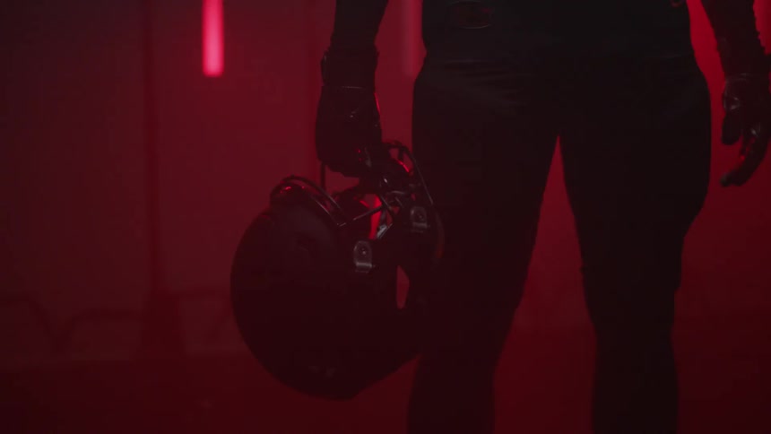 A football player holds his helmet in a room with flashing lights