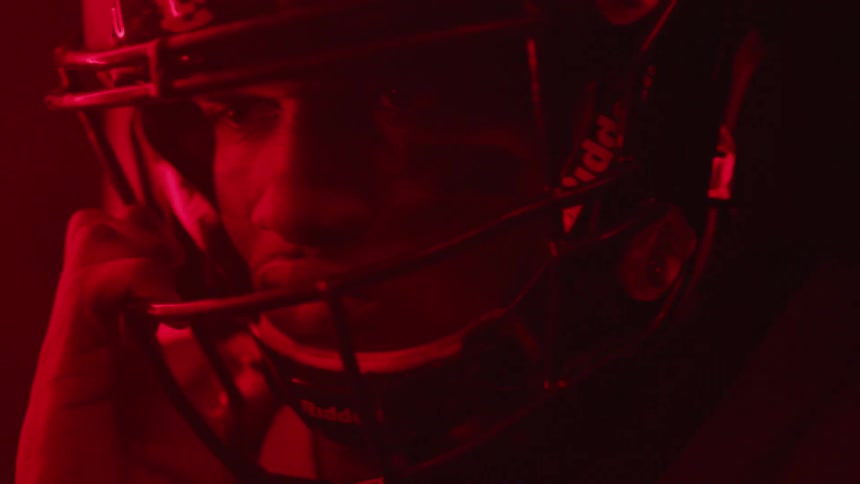 A man stands with a football helmet on