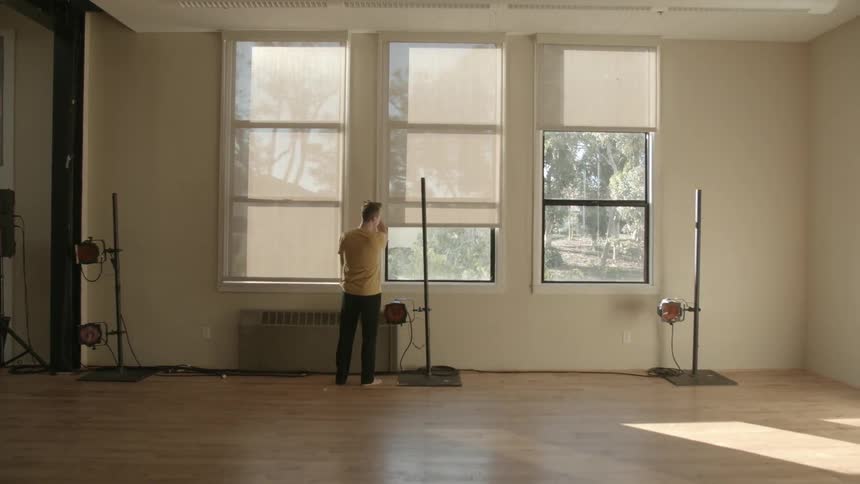 A man walks into a dance studio and opens the window shades