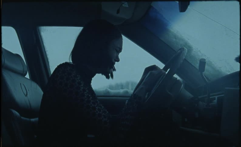Woman sits crying in a parked car