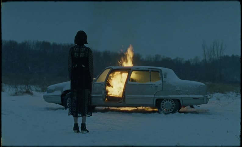 Woman watches car burning in the snow