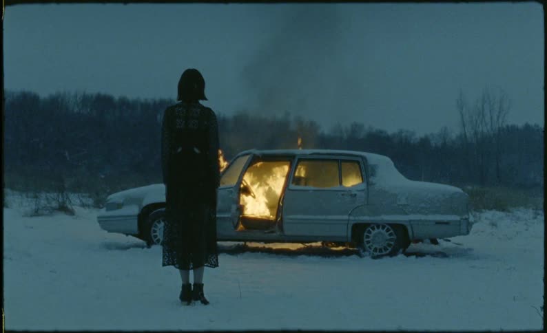 A woman watches her vehicle burn in the snow