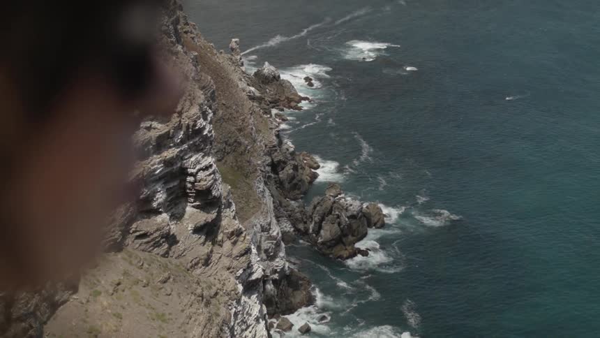 Woman standing on a high cliff overlooking water